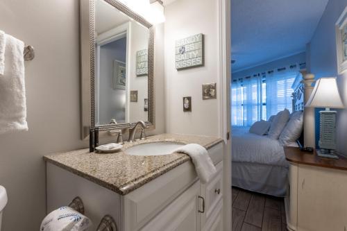 a bathroom with a sink and a mirror and a bed at Harbour Place 510 in Gulf Shores
