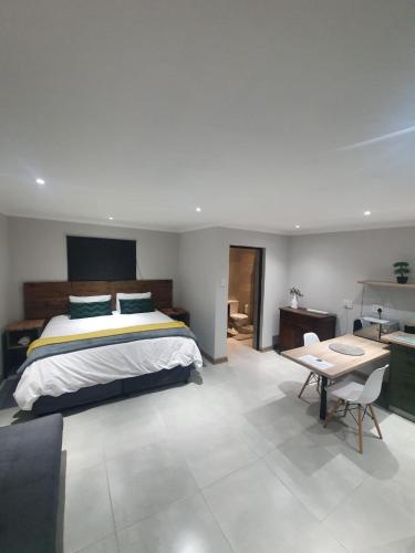 a bedroom with a bed and a table in it at bird haven self catering in Donny-brook