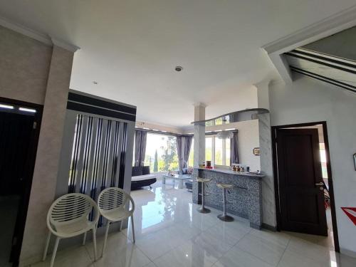 a large living room with chairs and a kitchen at Villa Mahlin 3 kamar in Tutugan