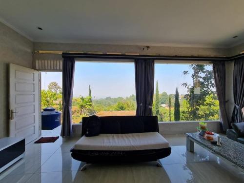a living room with a couch and a large window at Villa Mahlin 3 kamar in Tutugan