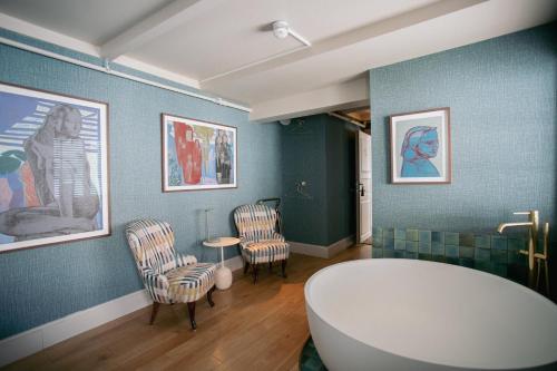 ein Badezimmer mit Badewanne, zwei Stühlen und einem Tisch in der Unterkunft Gamlekaien in Skudeneshavn
