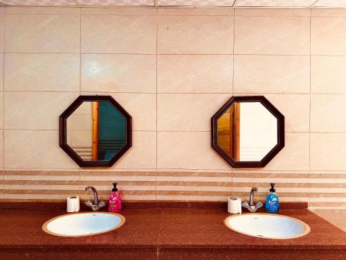 two sinks in a public bathroom with two mirrors at Wadi Rum Magic Nature Camp in Wadi Rum
