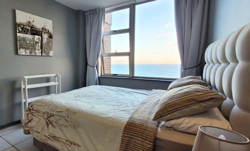 a bedroom with a bed and a large window at Scottburgh Views 707 Seafront Apartment in Scottburgh