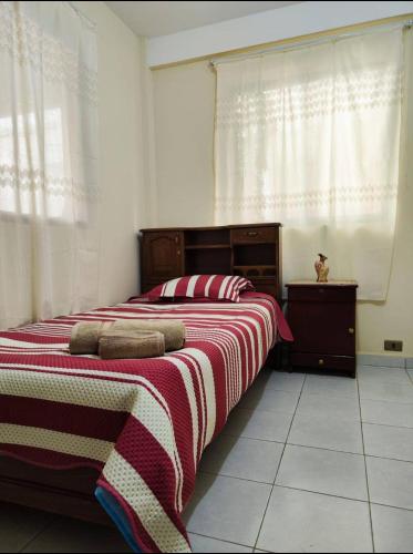 a bedroom with a bed with a red and white blanket at Valle Dorado Residence in Colcapirhua