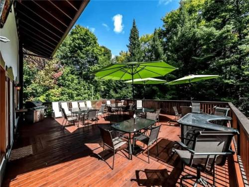 a deck with tables and chairs and an umbrella at Genteman Manor Private Indoor Pool Sauna & Lake in Sainte-Agathe-des-Monts