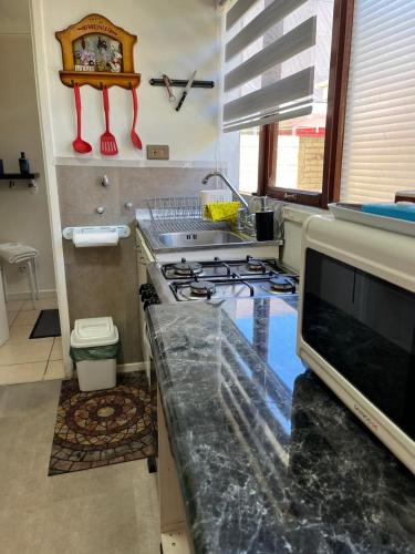 a kitchen with a sink and a stove top oven at Caiquén Cabaña Punta Arenas in El Cerrillo