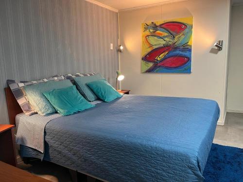 a bedroom with a blue bed with a painting on the wall at Caiquén Cabaña Punta Arenas in El Cerrillo