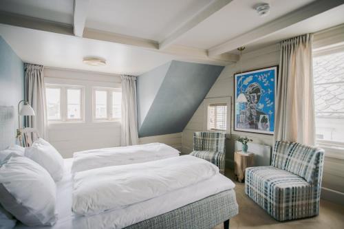 ein Schlafzimmer mit einem Bett und zwei Stühlen in der Unterkunft Gamlekaien in Skudeneshavn