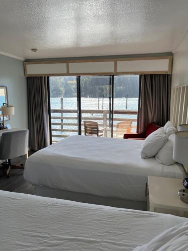 a hotel room with two beds and a balcony at River House Inn, a Baymont by Wyndham in Florence