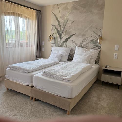 two beds in a bedroom with a painting on the wall at Heritage Hall and More in Nagykálló