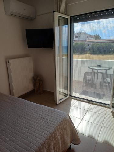 a bedroom with a bed and a balcony with a table at DANAI'S Sea Whisper in Lékhaion