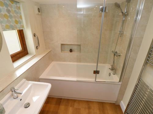 a bathroom with a shower and a tub and a sink at Brynawelon in Newport