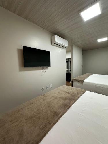 a bedroom with two beds and a flat screen tv at Miraflores Hotel in Macapá