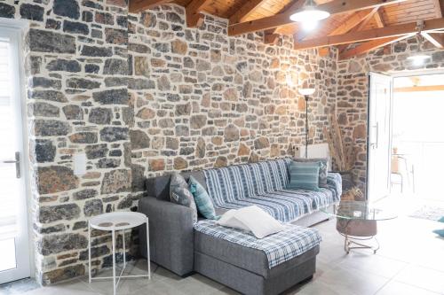 a living room with a stone wall with a couch at Πέτρινο Αλώνι in Panayía