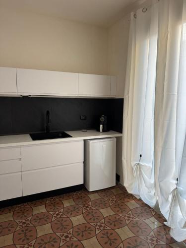 a kitchen with white cabinets and a sink next to a window at Marta House 2 in Trapani