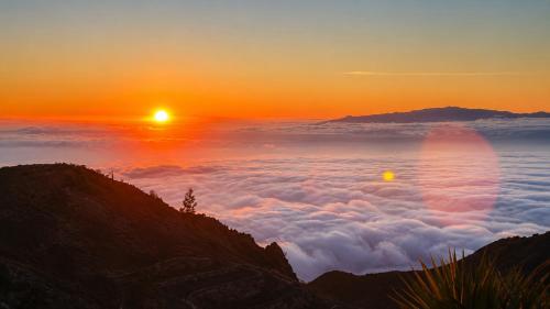 a view of the sun rising above a sea of clouds at Jardines de Ifonche in Ifonche