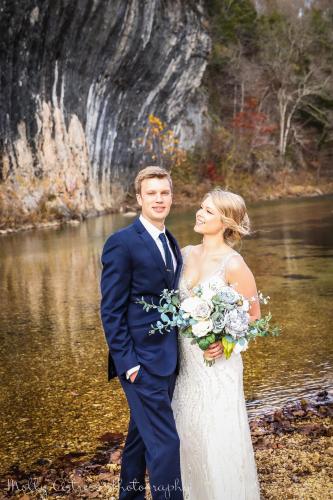 a bride and groom standing in front of a river at Echo Bluff State Park Lodge and Cabins in Eminence
