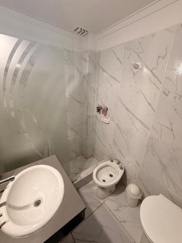 a white bathroom with a sink and a toilet at Cristal Hotel in Eduardo Castex
