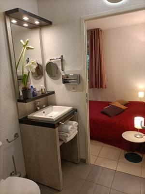 a bathroom with a sink and a red bed at Résidence de la Source by Euclenima in Salies-de-Béarn