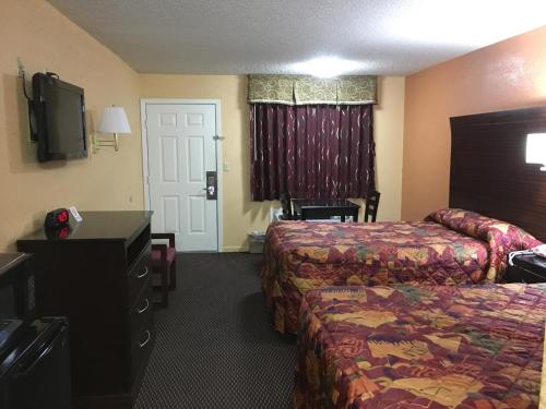 a hotel room with two beds and a flat screen tv at Redwood Inn - White Hall in White Hall
