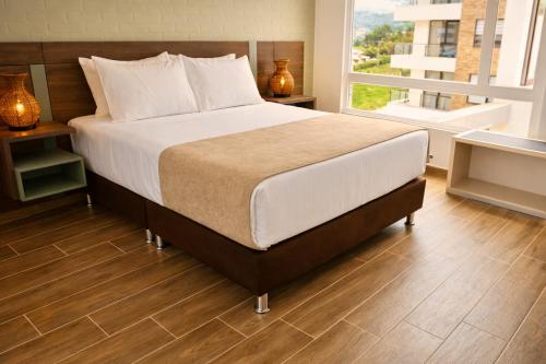 a bedroom with a large bed and a large window at Lago Verde Elit in Paipa
