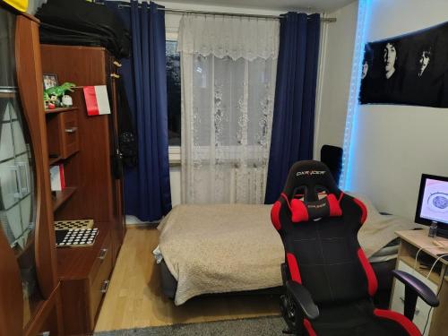 a bedroom with a bed and a chair in front of a window at Chelm Spoko Apartment in Chełm