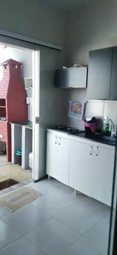 a kitchen with white cabinets and a stove in it at Casinha Larithur in Beberibe