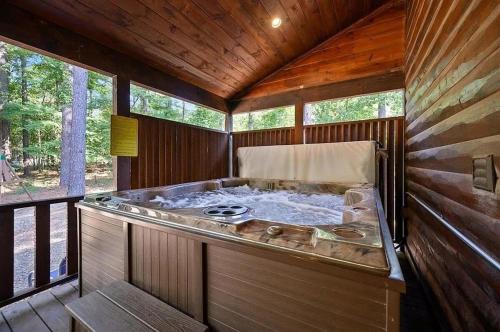 a jacuzzi tub in a wooden house at Big Pine Gathering - Heated Pool - Pickleball - Sleeps 16 in Broken Bow