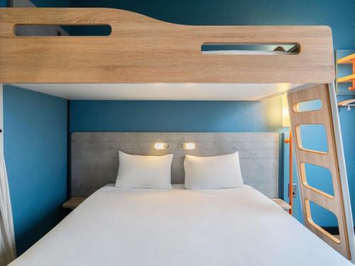 a bunk bed with white pillows and a ladder at ibis budget Genève Aéroport in Geneva