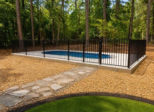 a black iron fence with a pool in a yard at Big Pine Gathering - Heated Pool - Pickleball - Sleeps 16 in Broken Bow