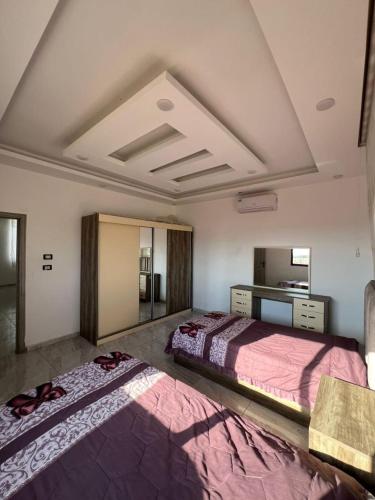 two beds in a large room with a ceiling at Al Salty in Tall ar Rāmah