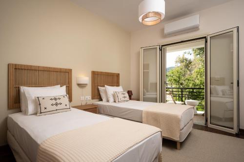 two beds in a hotel room with a balcony at Sandy Pines Villas in Alykes