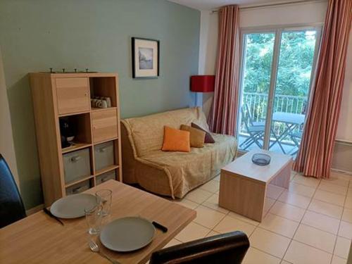 a living room with a couch and a table at Résidence de la Source by Euclenima in Salies-de-Béarn