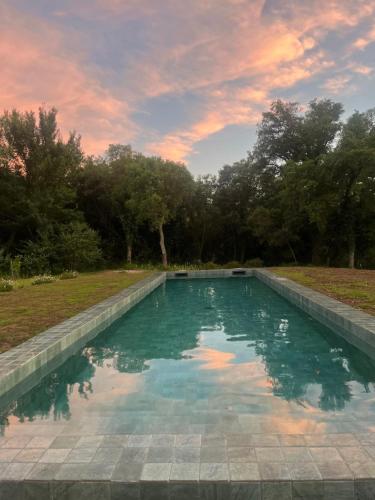 a swimming pool with a sunset in the background at Les Plaines in La Môle