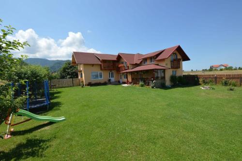 a house with a yard with a playground at Pensiunea Gratiela in Stațiunea Climaterică Sâmbăta
