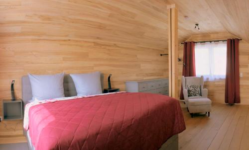 a bedroom with a red bed and a chair at Ferienhäuser Ilsensee Schillingsfürst in Schillingsfürst