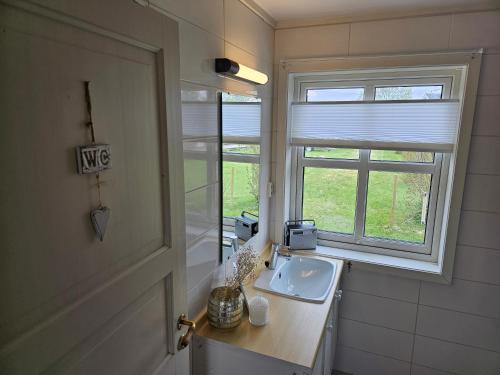 a bathroom with a sink and a window at Hammergaarden Stabbursstua - Heritage Loft Stay in Sortland