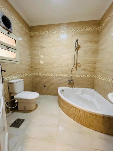 a bathroom with a tub and a toilet and a sink at Aura Downtown Suites in Cairo