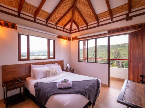 a bedroom with a large white bed with windows at Artemisa Hotel Villa de Leyva in Santa Sofía