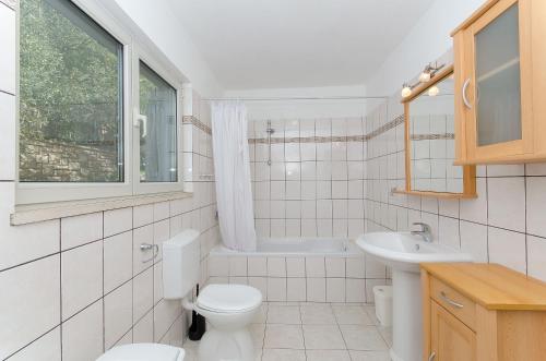 a white bathroom with a toilet and a sink at Apartment Seaside Peace in Vela Luka