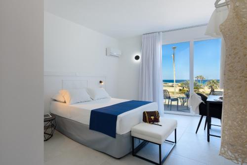 a bedroom with a bed and a desk and a balcony at Sea View Hotel Fronte Mare in San Vito lo Capo
