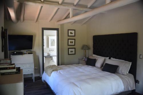 1 dormitorio con 1 cama blanca grande y TV de pantalla plana en Hotel MasClara, en Villa de Leyva