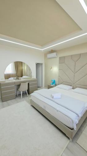 a white bedroom with a large bed and a desk at Selimi House in Shirokë