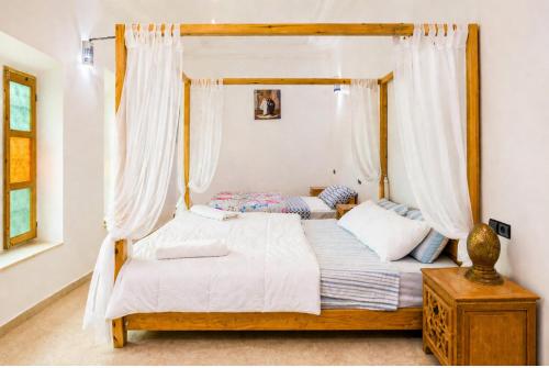 a bedroom with a canopy bed with white curtains at Kasbah ben hamou in Nkob