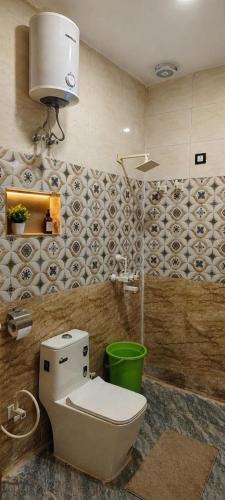 a bathroom with a toilet and a green bucket at Hotel Urban Inn - The RK Hospitality Group #Prem Mandir #Chaar Dham Fully AC in Vrindāvan