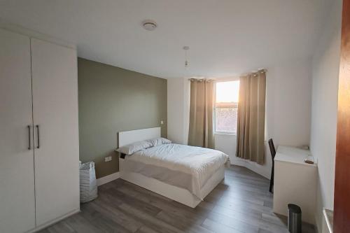 a bedroom with a white bed and a window at Jurassic Coast Gateway Exmouth Escape in Exmouth