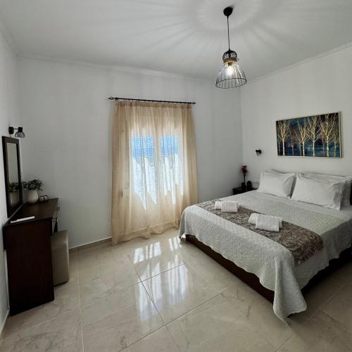 a white bedroom with a large bed and a window at Baloma Apartment in Falasarna