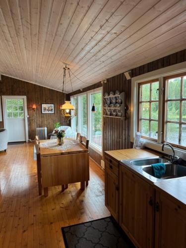a large kitchen with a wooden ceiling and a table at Lakeside cabin in Snofugl