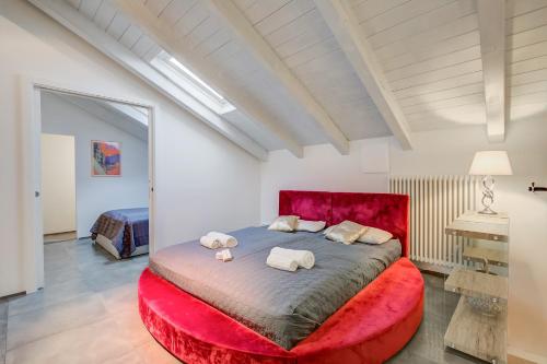 a bedroom with a large red bed with two towels at Loft & Jacuzzi - Happy Rentals in Riva del Garda