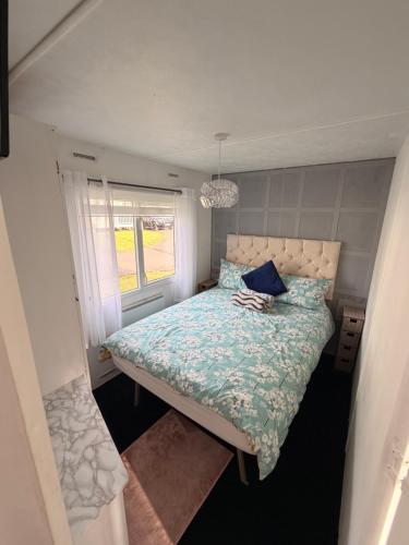 a small bedroom with a bed and a window at Hoopers Hideaway Caravan Rental SetonSands 2 in Port Seton
